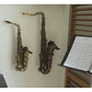 customer home interior image with vertical tenor and alto saxophones on white wall next to sheet music